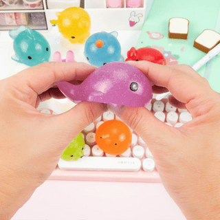 A purple whale squishy getting stretched with two hands.