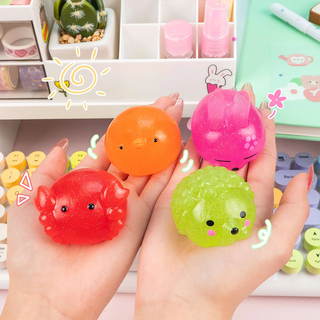 Four colorful squishies shaped like animals held in two hands, palm up, with a desktop background.