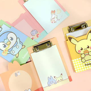 Set of four colorful clipboards with pastel Pokemon designs on them over a pink background. The covers of the clipboards are open showing the memo pads with Pokemon designs on them.
