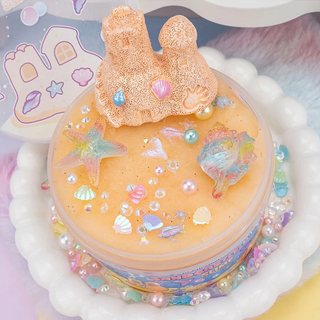 Sandcastle slime in its container with sea-themed charms on top.